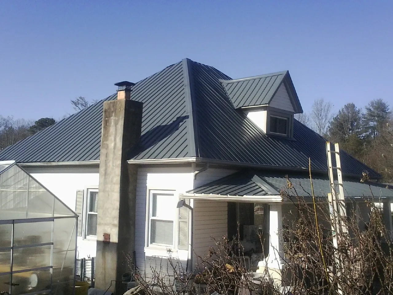 Dark blue standing seam metal roof on a white farmhouse with dormer — Slate & Tile Roof Repair by Roofing Brothers in Camas