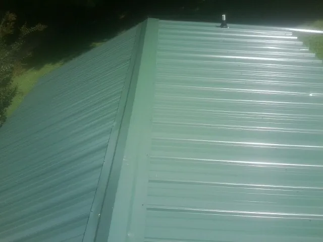 New green metal panels meeting at the ridge of a roof — Flat Roof Repair work by our crew in Camas