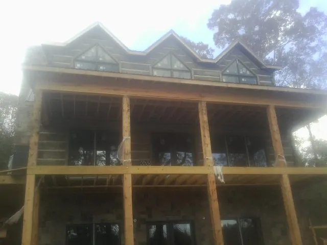 Dormers and porch framing on a large log home under construction — Roof Coating work by our crew in Camas